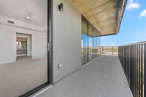 A balcony with a glass railing and a concrete floor.