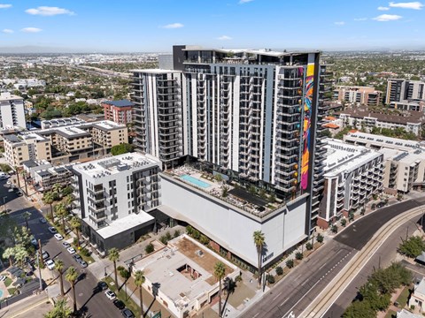 A tall building with a colorful design on the side stands out in a cityscape.