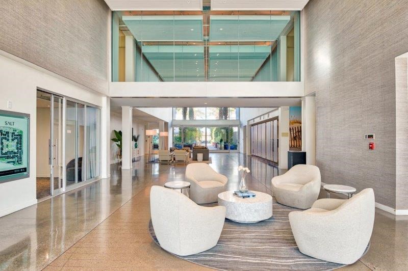 the lobby of a building with white chairs and tables