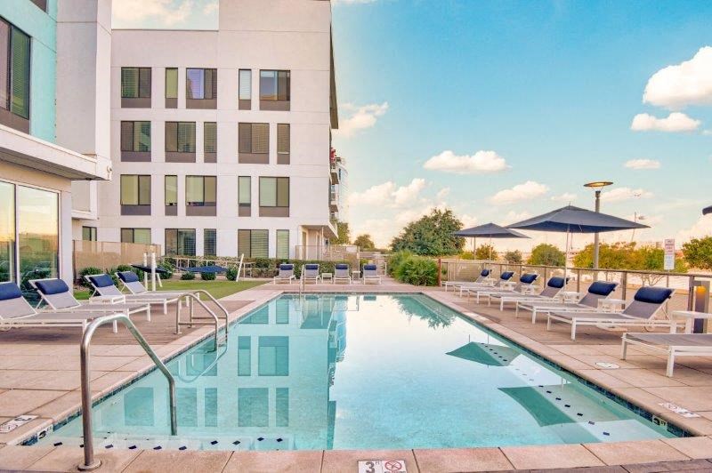 a swimming pool with chairs and a building in the background