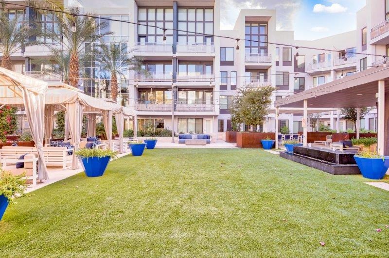a large grassy courtyard with a fire pit in front of an apartment building