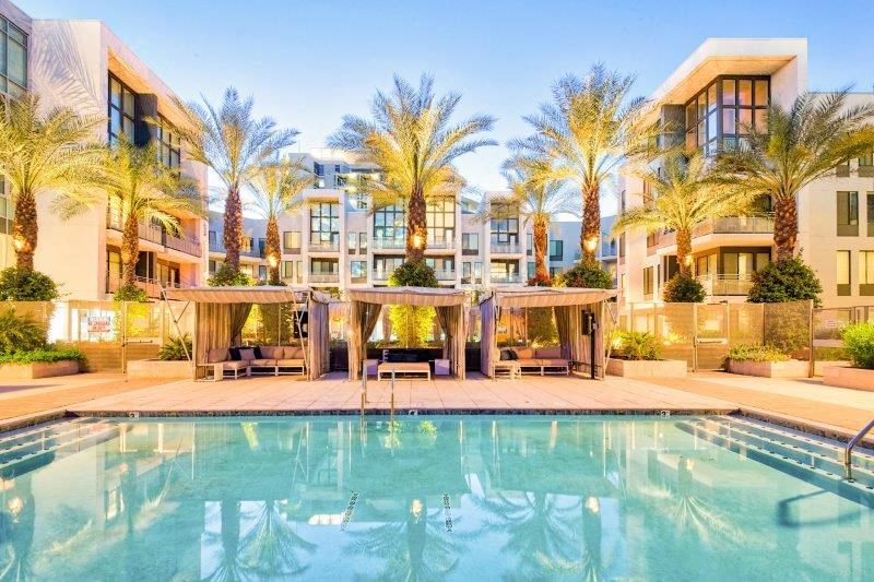 a swimming pool with palm trees and buildings in the background