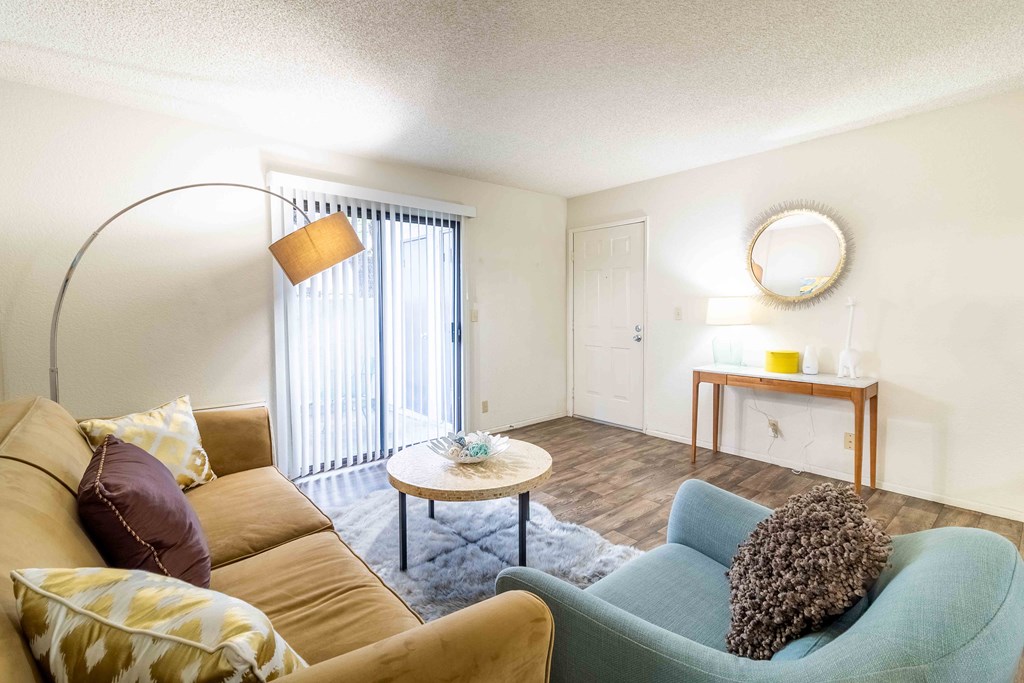 A living room with a yellow couch, a blue chair, and a small table with candles on it.