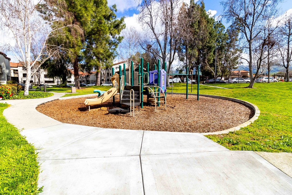 A playground with a slide and swings in a park.