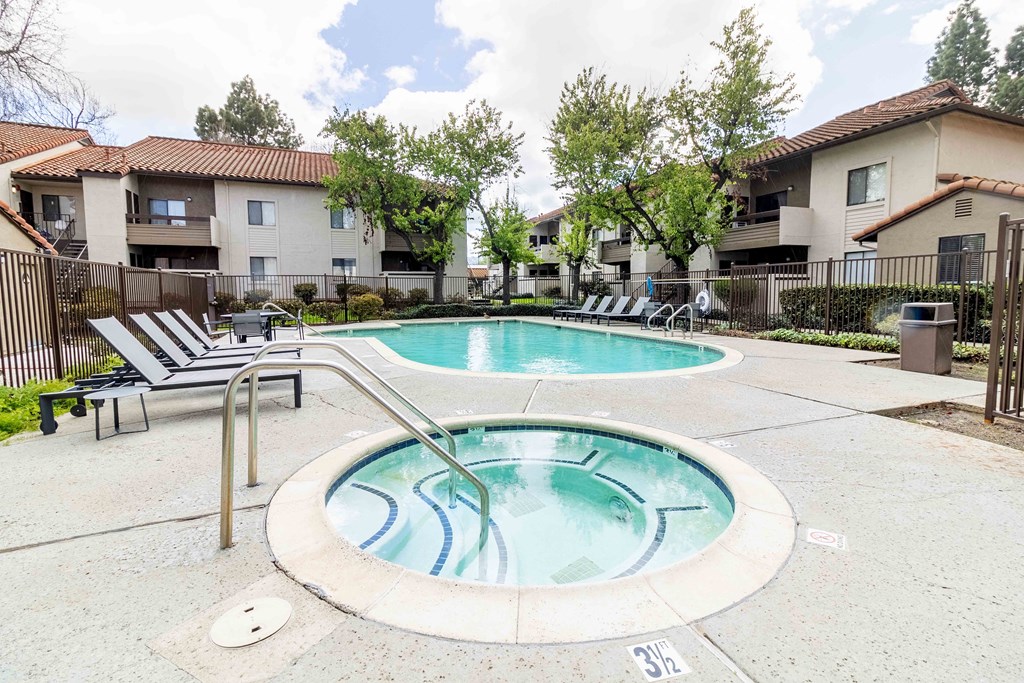 A small pool with a metal ladder in front of apartment buildings.