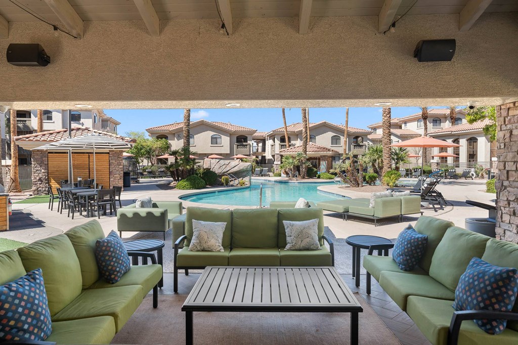 A patio with a pool and green couches.