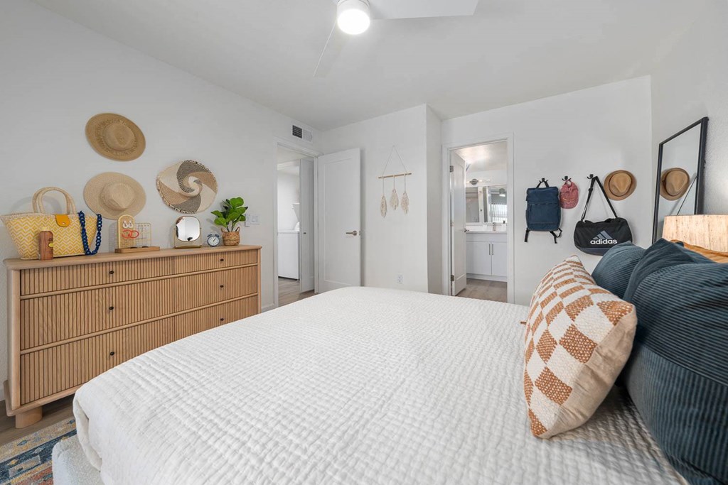 a bedroom with a bed and a dresser with hats on it