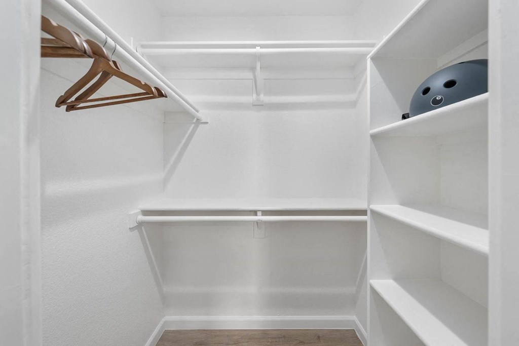 a walk in closet with white shelves and a white closet door