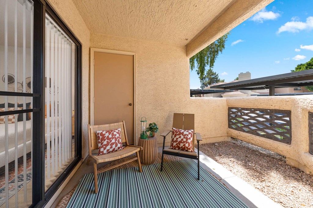 a balcony with two chairs and a sliding glass door