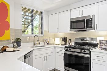 A modern kitchen with white cabinets and a black stove top oven.