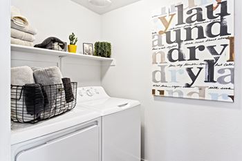 A laundry room with a washer and dryer and a wall hanging with words.