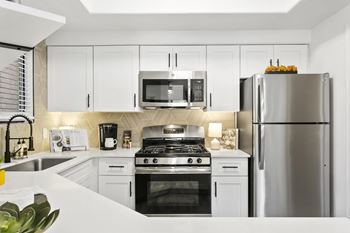 A modern kitchen with a stainless steel refrigerator, oven, and microwave.
