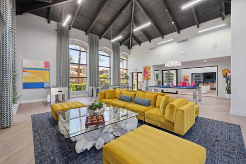A modern living room with a yellow sofa and glass coffee table.