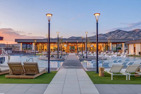 A poolside area with lounge chairs and a building in the background.