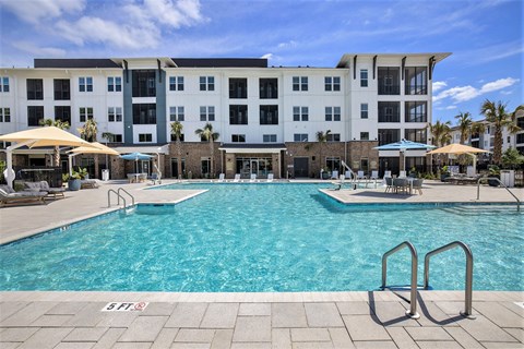 A large swimming pool in front of a multi-story building.