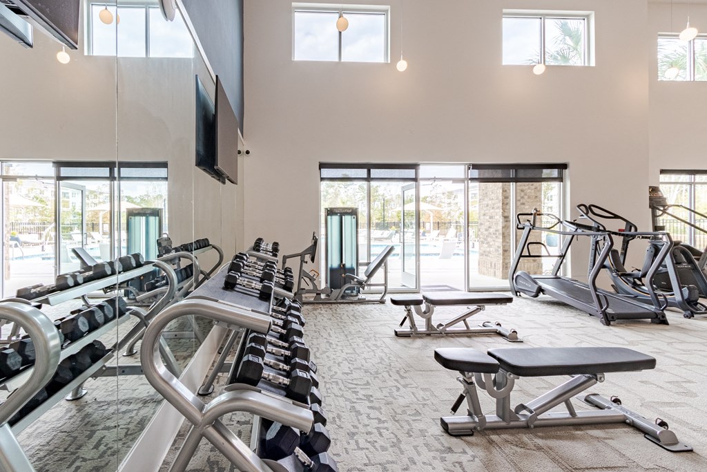 A gym with a variety of equipment including treadmills, weights, and exercise machines.