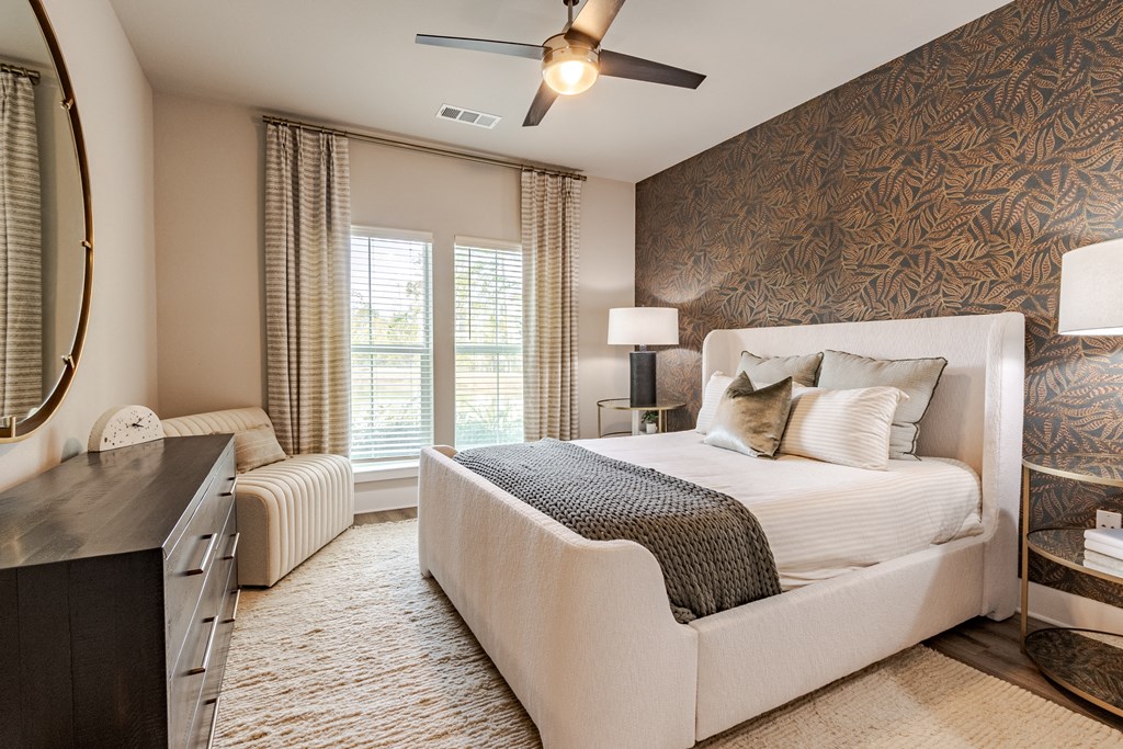A bedroom with a large bed, a dresser, and a ceiling fan.