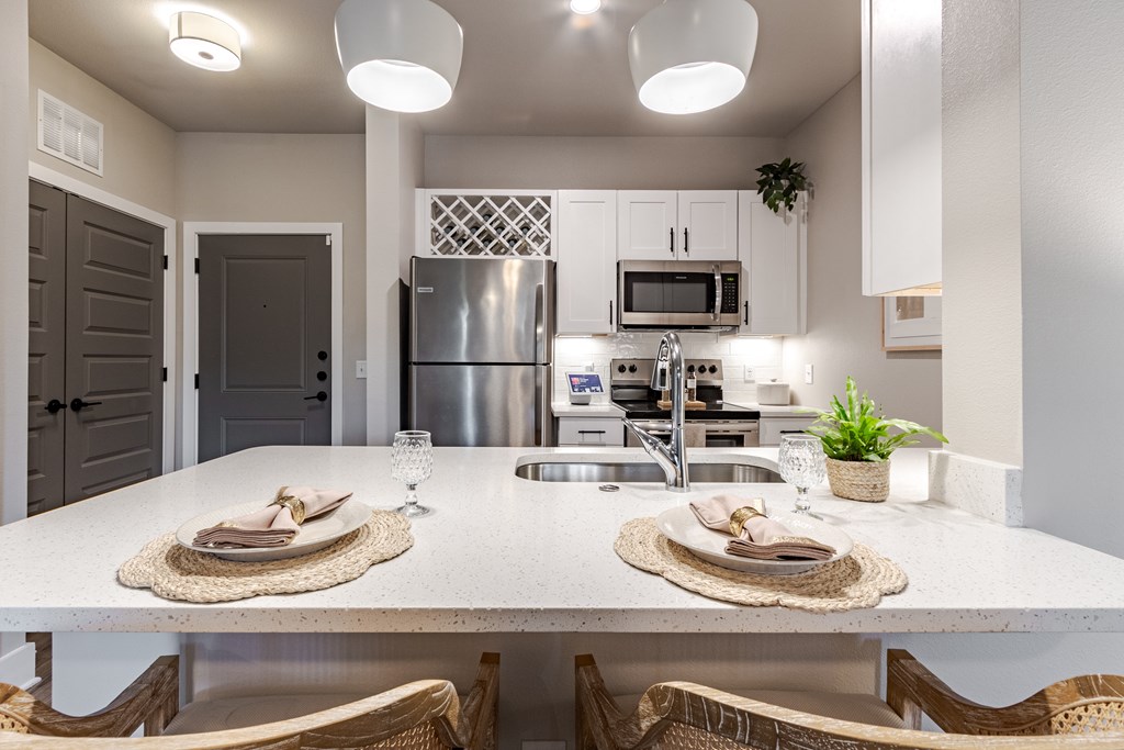 A modern kitchen with a dining table set for two.