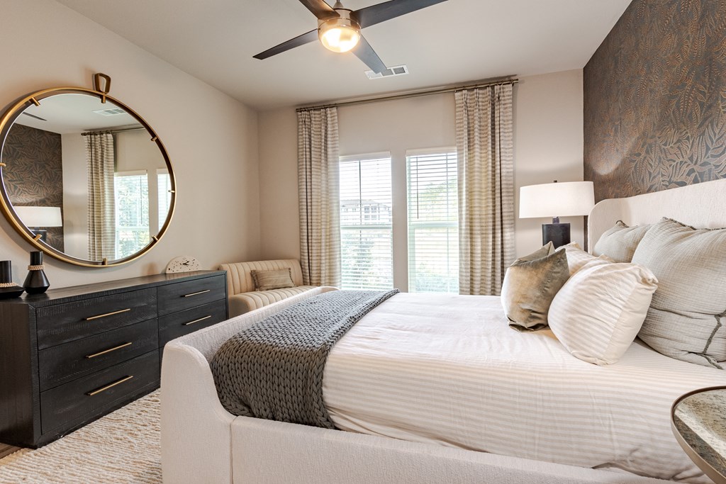 A bedroom with a large bed, a dresser, and a ceiling fan.
