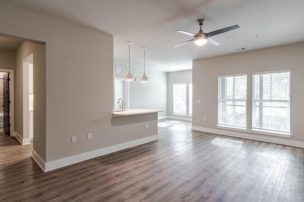 A spacious living room with a ceiling fan and hardwood floors.