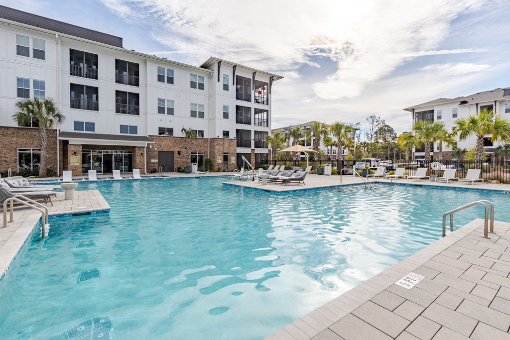 A large swimming pool in front of a multi-story apartment building.