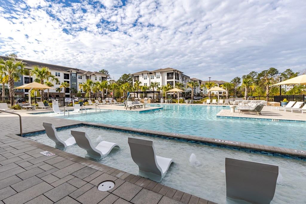 A pool with chairs around it and a building in the background.