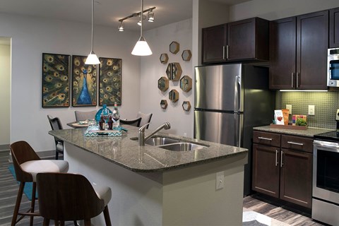 A kitchen with a granite countertop and a stainless steel refrigerator.