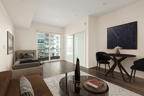 A modern living room with a grey sofa, a black chair, a coffee table, and a painting on the wall.