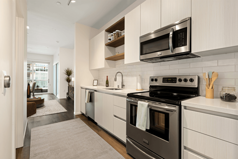 A modern kitchen with a black stove top oven and white cabinets.