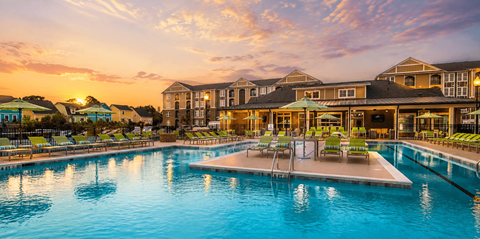 A large swimming pool in front of a resort at sunset.