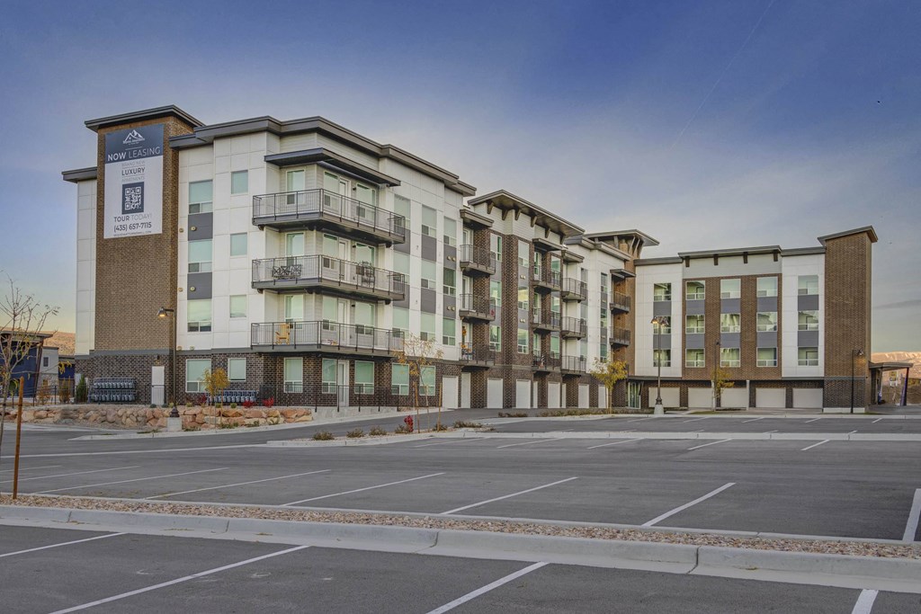 A large apartment complex with a parking lot in front.