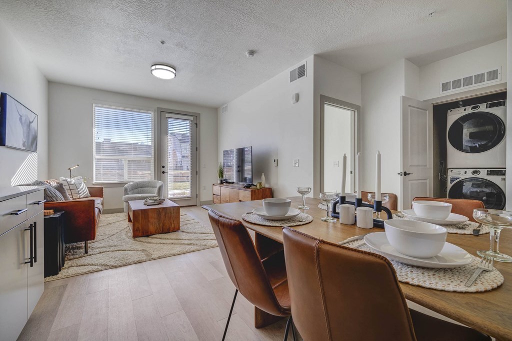 A modern kitchen with brown chairs and a dining table set for two.