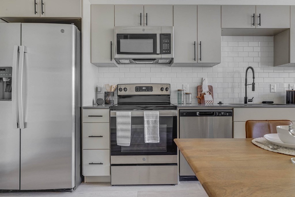 A modern kitchen with a refrigerator, oven, and microwave.