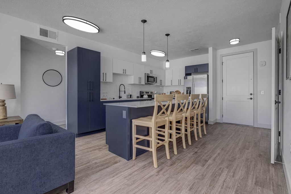 A kitchen with a blue couch and wooden chairs.