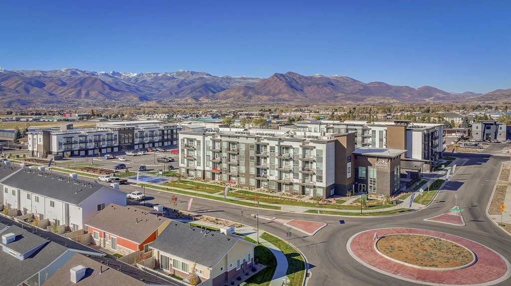 A modern residential area with a large building in the center and mountains in the background.