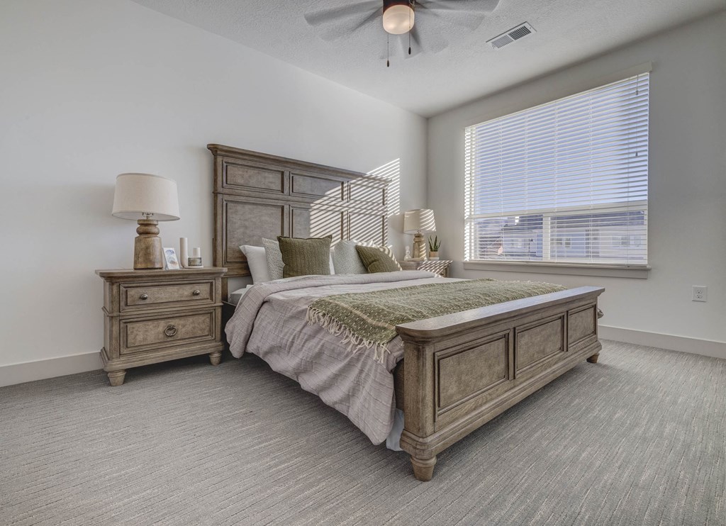 A bedroom with a large bed and a dresser with a lamp on it.