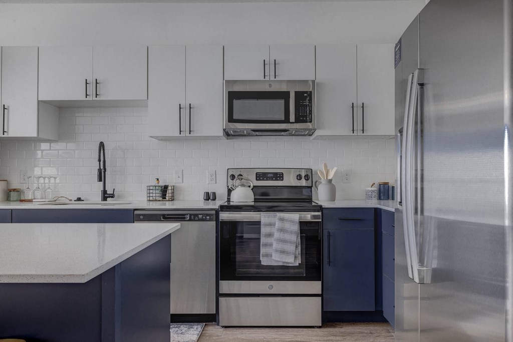 A modern kitchen with a stainless steel refrigerator and a microwave above the stove.