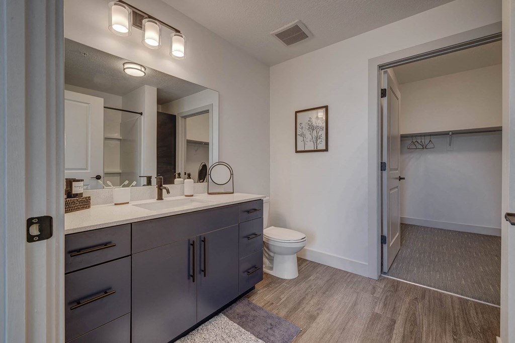A bathroom with a toilet, sink, and mirror.