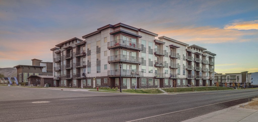 A large apartment building with balconies is captured during sunset.