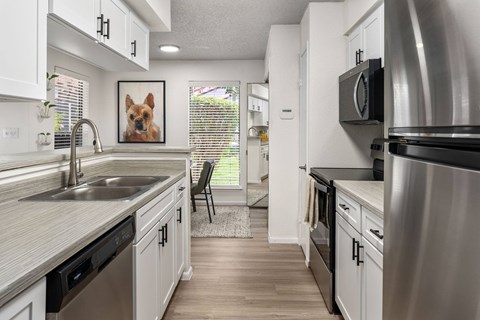 A kitchen with a stainless steel refrigerator and black appliances.