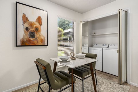 A kitchen with a table and chairs and a painting of a dog on the wall.