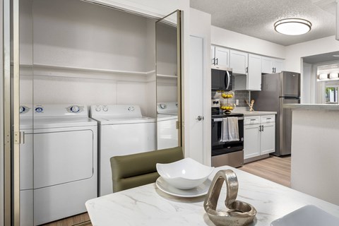 A modern kitchen with white appliances and a marble table.