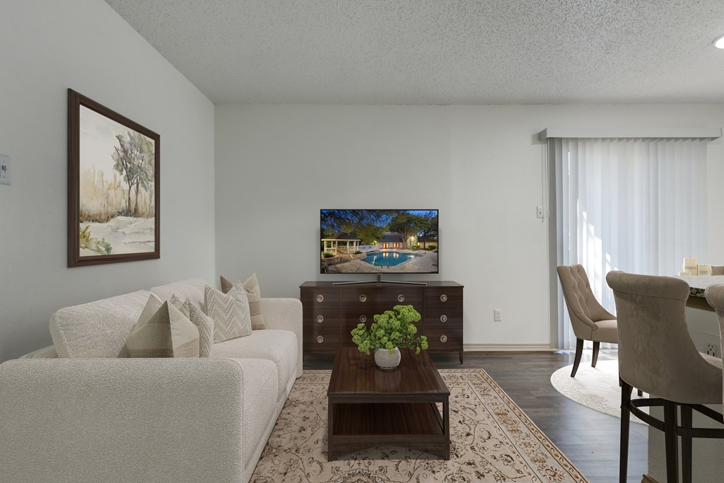 A living room with a white couch, a wooden coffee table, and a painting on the wall.