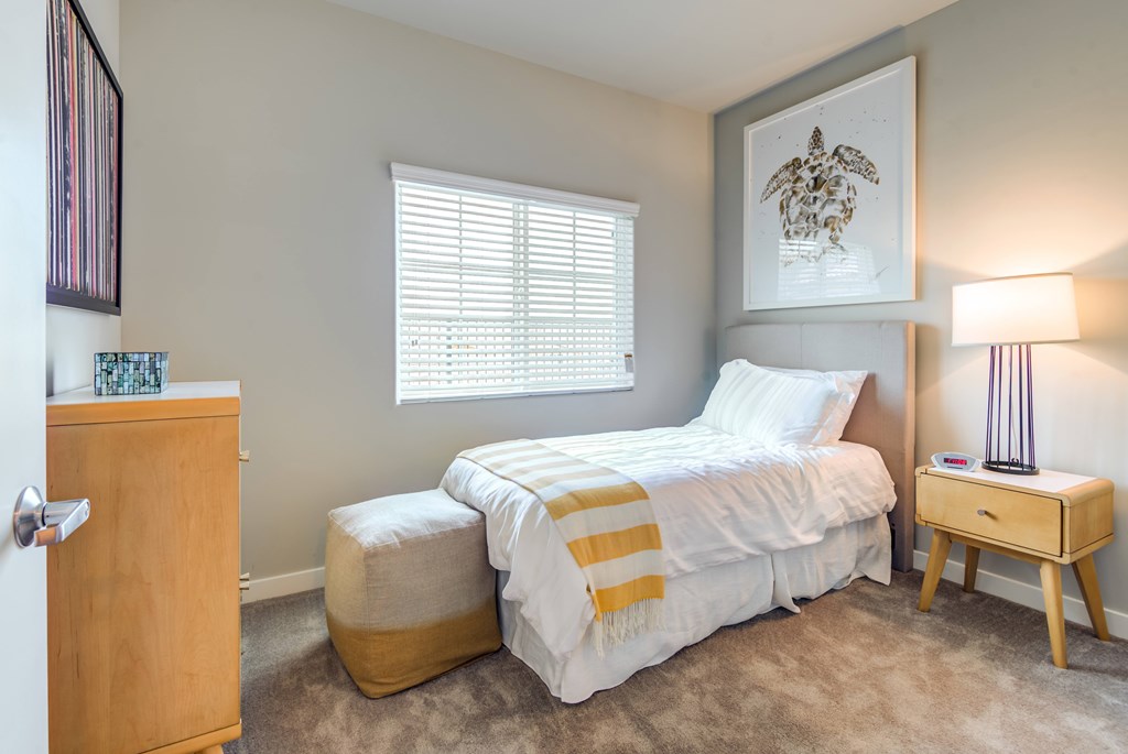 A bedroom with a bed, nightstand, and lamp.