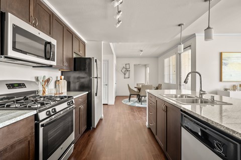 A modern kitchen with dark wood cabinets and stainless steel appliances.