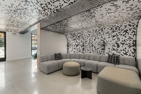A room with a black and white patterned ceiling and grey furniture.