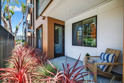 A modern patio with a wooden chair and a potted plant.