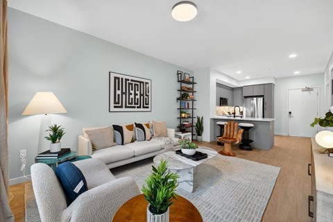 A living room with a grey couch, a wooden table, and a bookshelf.