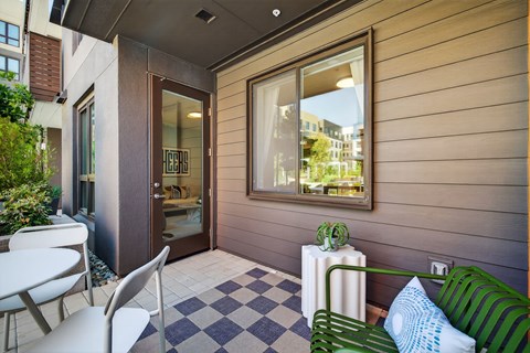 A patio with a green bench, a white table and a black and white checkered floor.