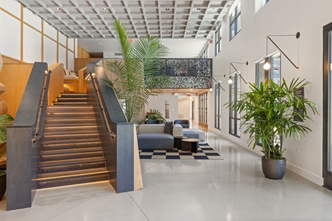 A modern interior with a staircase, plants, and a sofa.